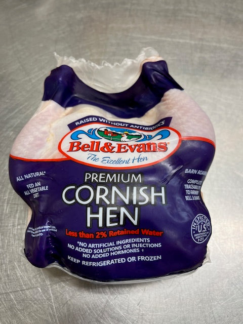 Cornish Hen wrapped in package by bell & evans with details of excellent hens on a metal cutting board. 