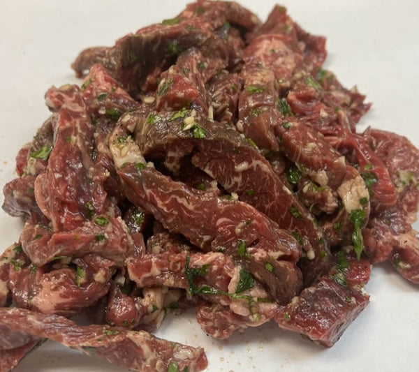 strips of raw marinated and seasoned skirt steak on white butcher paper