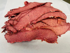 Sliced pastrami on a white cutting board