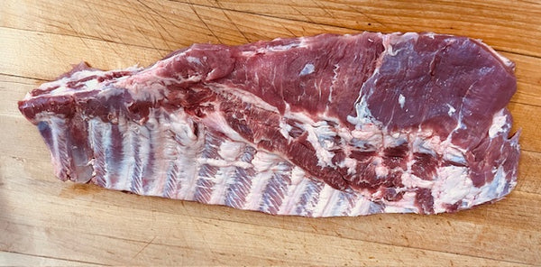 Raw flat spare ribs on a wooden cutting board