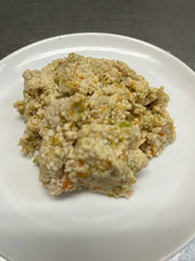 a pile of chicken dog food on white plate with visible grains and vegetables