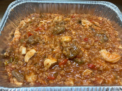 A foil pan containing jambalaya, a Cajun dish made with rice, meat, and vegetables.