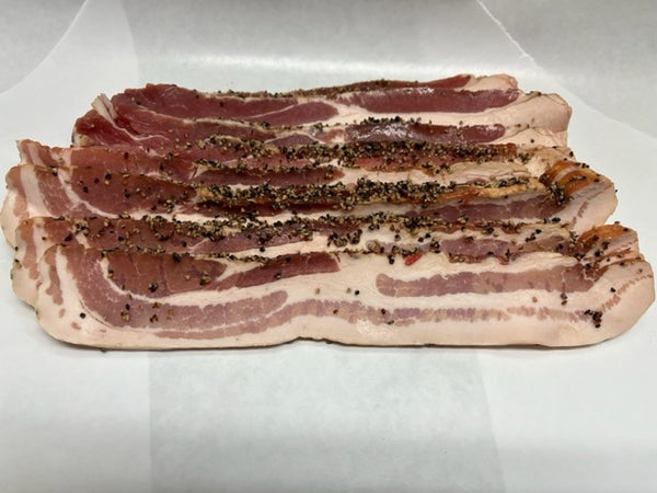 A pile of pepper-coated bacon slices on a white paper.