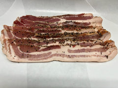 A pile of pepper-coated bacon slices on a white paper.