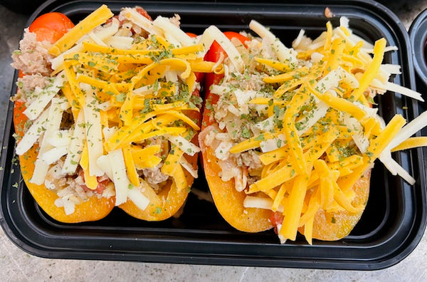 Stuff peppers with visible peppers, meat, cheese and herbs in a black travel container. 