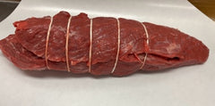 A chuck eye roast, also known as Jewish tenderloin, tied with strings on a white surface.
