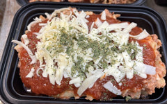 Prepared ziti with red sauce, cheese, and herbs in a black plastic container.