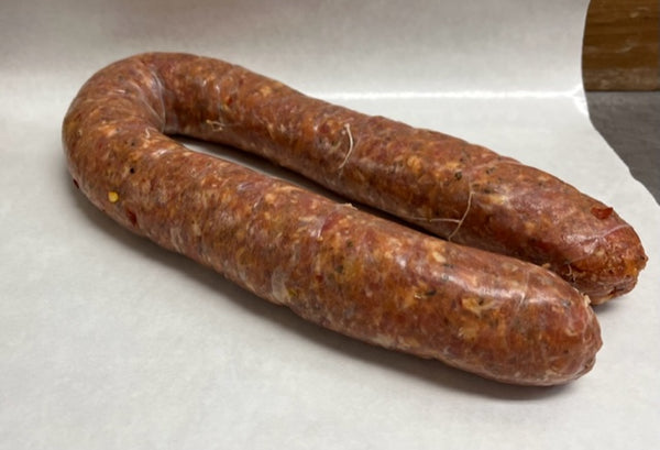 A rope of fresh chorizo sausages on a white butcher paper 
