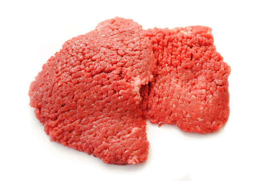 Two swiss steaks laying with a white background. 