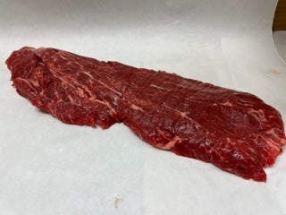 A raw flat iron steak on a white surface.