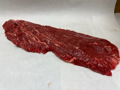 A raw flat iron steak on a white surface.