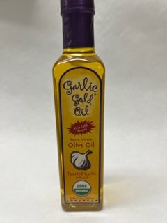 A bottle of Garlic Gold Olive Oil with a purple cap on a white background.