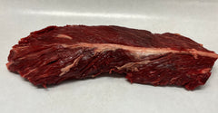 A hanger steak on a white butcher paper, displaying its raw, red meat texture.
