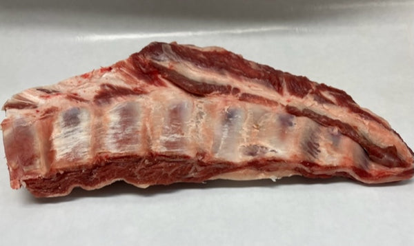 A piece of lamb breast meat on a white butcher paper.