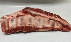 A piece of lamb breast meat on a white butcher paper.