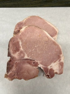 A raw center-cut loin pork chop on a white surface.