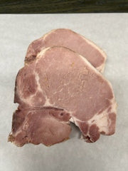 A raw center-cut loin pork chop on a white surface.