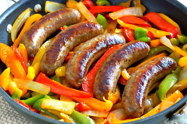 blackpan with four links of cooked sausage peppers and onions