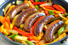 blackpan with four links of cooked sausage peppers and onions