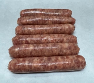 A stack of small link sausages on a white surface.