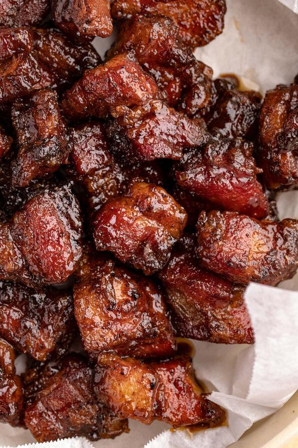 A close-up image of smoked pork tips, showcasing a crispy and well-cooked texture, served on a paper plate.