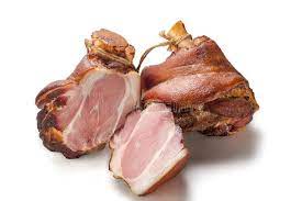 Two pork shanks, one whole and one cut into pieces, on a white background.