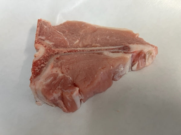 A piece of veal loin chop on a white paper.