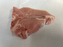 A piece of veal loin chop on a white paper.