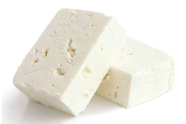 A pre-cut block of white feta cheese on a white background.