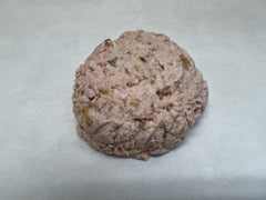 A ball of ham salad on a white butcher paper . containing herbs and spices.