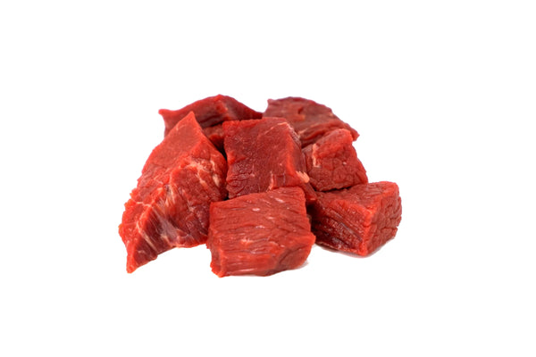 A pile of raw lamb kabobs on a white butcher paper.