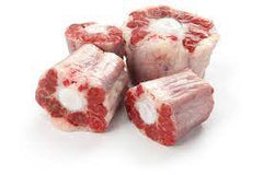 Cut up oxtail meat displayed on a white background.