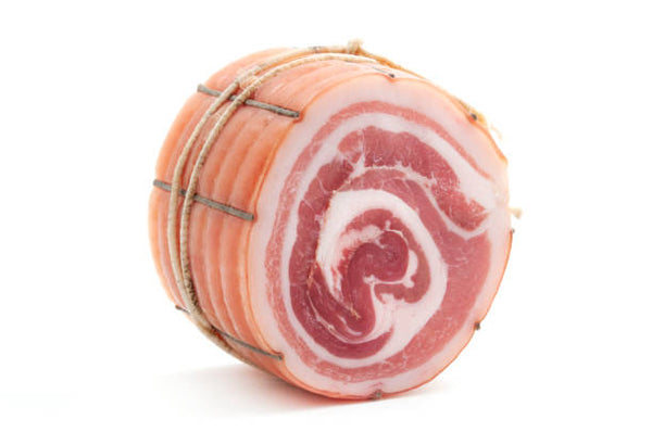 Rope wrapped pancetta cut in a thick chuck on a white surface. 