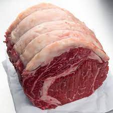 A rolled raw beef rib eye roast on white butcher paper