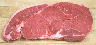 A fresh beef sirloin top butt roast on a wooden cutting board.