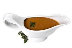 A white gravy boat of turkey gravy, garnished with a sprig of parsley. against a white background